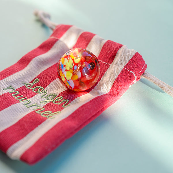 Kraftmurmel aus Muranoglas (Rot mit Konfetti-Steinchen) 25mm, in hochwertigem Stoffbeutel mit Stickerei